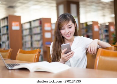 Asian Beautiful Female Student Using Mobile Phone In Library