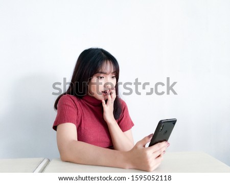 Asian beautiful girl is shocked in the smartphone on the isolated white background