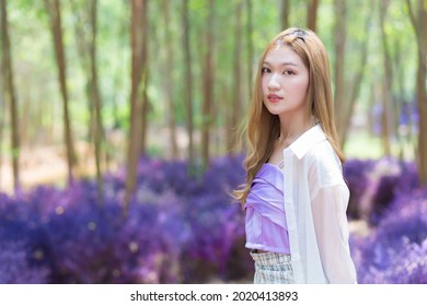 Asian beautiful girl wearing white long shirt smiles happily and stands in the garden as natural theme. - Powered by Shutterstock