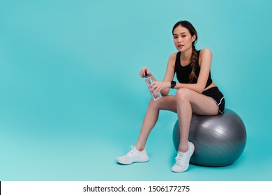 Asian beautiful happy woman holding water bottle and sitting on fit ball after exercise isolated on blue color background.Concept of slim and healthy girl workout. - Shutterstock ID 1506177275