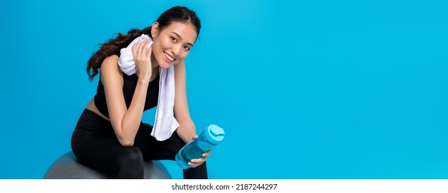Asian beautiful happy woman holding water bottle and sitting on fit ball after exercise isolated on blue background.Concept of slim and healthy girl workout. - Shutterstock ID 2187244297