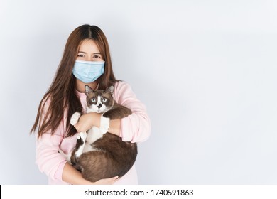 Asian Beautiful Happy Woman Wearing A Medical Protection Face Mask For Protect The Coronavirus, Filter Dust PM 2.5, Cold And Allergic To Cat Fur And She Carry A Cat On The White Background