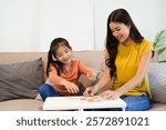 Asian beautiful loving mom playing game with daughter in house. Attractive woman parent spend free leisure time with young little girl child spend time learn and develop skill with kid