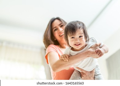Asian beautiful mother holding cute baby in arm swinging as airplane. Kid smiling and enjoy playing with mom. Child feeling fun and happy expression on face. Love care and relation in family concept.