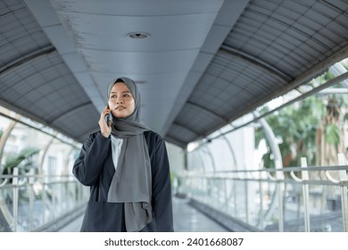 Asian beautiful muslim woman wear hijab talking with mobile phone. Islamic female walking and using telephone warking city street. - Powered by Shutterstock