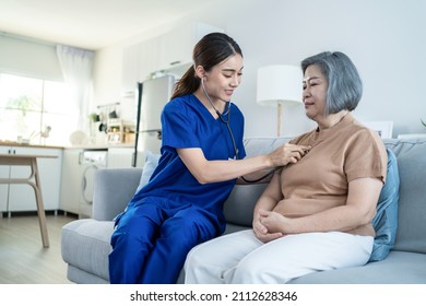 Asian Beautiful Nurse At Nursing Home Take Care Senior Elderly Woman. Beautiful Therapist Doctor Measure Heart Rate By Stethoscope On Female Older Patient On Sofa. Medical Insurance Service Concept.