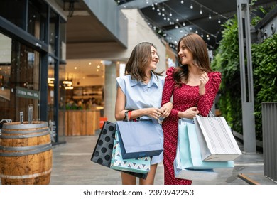 Asian beautiful two women shopping goods outdoor in department store. Attractive young female friend holding shopping bags then walking with happiness enjoy purchasing in shopping mall center together - Powered by Shutterstock