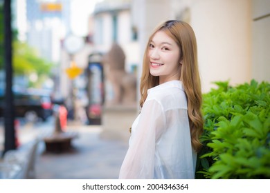 Asian Beautiful Woman With Bronze Hair Turn S Around In White Shirt While Walks On Street.