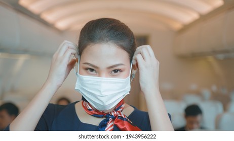 An Asian Beautiful Woman Cabin Crew Is Wearing Protective Mask Onboard , Taking Of Face Mask And Smiling , Safe Travel , COVID-19 Protection Concept ..	