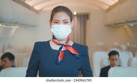 An Asian Beautiful Woman Cabin Crew Is Wearing Protective Mask Onboard , Taking Of Face Mask And Smiling , Safe Travel , COVID-19 Protection Concept ..	