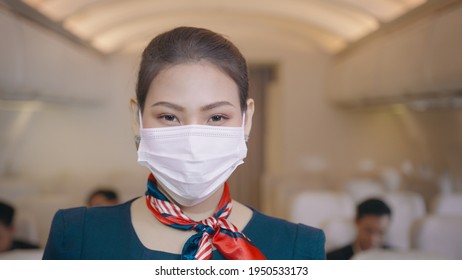 An Asian Beautiful Woman Cabin Crew Is Wearing Protective Mask Onboard , Taking Of Face Mask And Smiling , Safe Travel , COVID-19 Protection Concept ..	