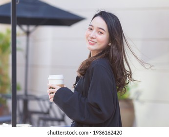 Asian beautiful woman in a dark blue suit is stand smile happy. In front of the coffee shop in the sunny morning