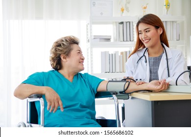 Asian Beautiful Woman Doctor Check The Pressure Of Old Lady Patients.The Female Doctor Smiled And Made Eye Contact With The Patient.