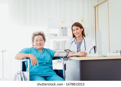 Asian Beautiful Woman Doctor Check The Pressure Of Old Lady Patients.The Female Doctor Smiled And Made Eye Contact With The Patient.