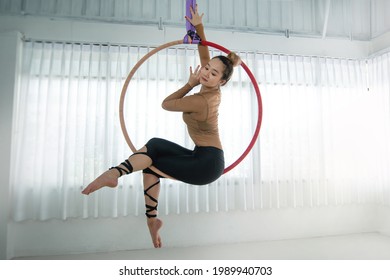 Asian beautiful woman doing aerial hoop or aerial ring practice at studio, woman hanging in aerial ring