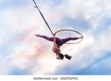 Asian beautiful woman doing aerial hoop or aerial ring practice outdoor. Woman hanging in aerial ring in the bright sky - Powered by Shutterstock