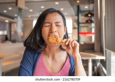 Asian beautiful woman enjoy eating with fried chicken. hungry woman looking, eating fried chicken, concept of delicious food, health care, eating habit, yummy fried chicken. - Shutterstock ID 2162780709