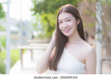 Asian Beautiful Woman With  Good Skin In Cream Shirt Standing Smiling Happily On Blurred Background.