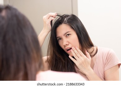 Asian beautiful woman look herself through mirror and pull her hair and touch her lip with worry about hair loss and grey hair.