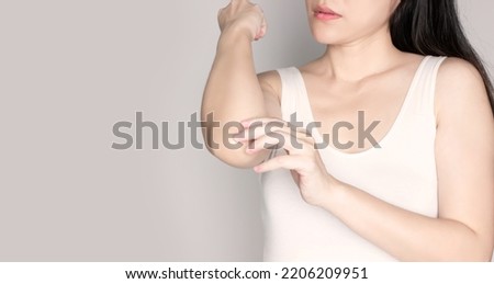 Asian beautiful woman looking elbow and her dryness skin and scratch and itchy, dryness of skin care with cosmetic makeup.