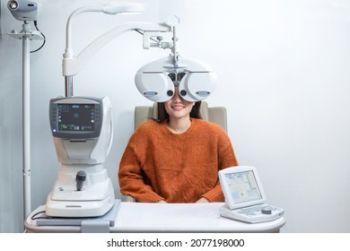 Asian beautiful woman looking through auto refractometer in modern ophthalmology clinic, eyesight test with modern equipment
