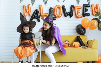 Asian Beautiful Woman Or Mother And Little Caucasian Sweet Girl Wearing And Dressing Up Halloween Costume With Hats, Playing Together With Fun, Smiling With Happiness, Celebrating Party At Home