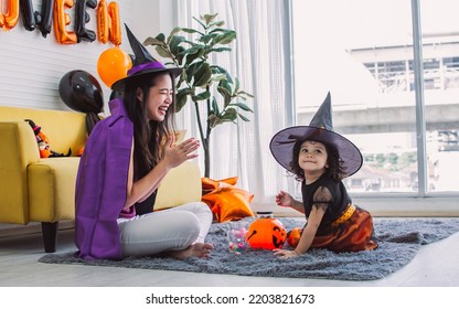 Asian Beautiful Woman Or Mother And Little Caucasian Sweet Girl Wearing And Dressing Up Halloween Costume With Hats, Playing Together With Fun, Smiling With Happiness, Celebrating Party At Home