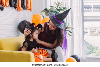 Asian Beautiful Woman Or Mother And Little Caucasian Sweet Girl Wearing And Dressing Up Halloween Costume With Hats, Playing Together With Fun, Smiling With Happiness, Celebrating Party At Home