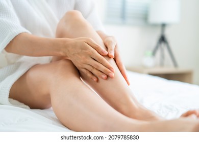 Asian Beautiful Woman Put Smooth And Soft Skin Care On Legs In Bedroom. Attractive Girl Touches Her Knee And Applying Cream Lotion For Rejuvenation With Gentle. Beauty, Skin Care And Health Concept.