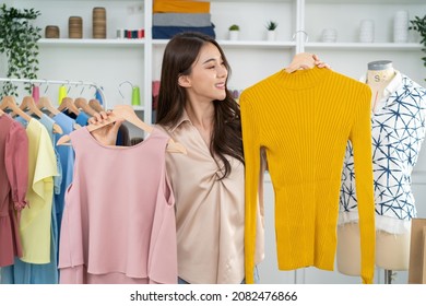 Asian beautiful woman sell cloth product online live streaming at home. Young female use mobile phone video call shows goods to customer and present detail. Remote buying and purchase shopping concept