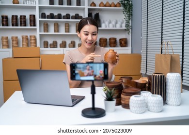 Asian beautiful woman sell vase product online live streaming at home. Young attractive girl use laptop computer shows goods to customer and present detail. Remote buying and purchase shopping concept - Shutterstock ID 2075023009