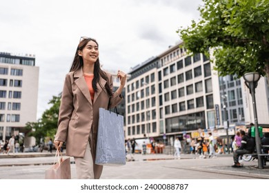 Asian beautiful woman shopping goods outdoor alone in department store. Attractive young girl holding shopping bags while walking with happiness enjoying purchasing goods in shopping mall center. - Powered by Shutterstock