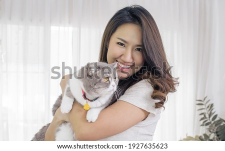 Asian beautiful woman smiling and hug her cat while taking rest at home. Lifestyle and Pet Concept.