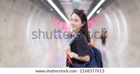 Asian beautiful woman tourist, wearing a black shirt, smiled into a subway tunnel and carried a backpack on the back.