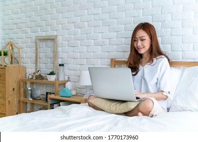 Asian Beautiful Woman Using Laptop Teleconference Meeting With Her Colleague From Home During Coronavirus Outbreak. Working From Home, Wfh, Staycation Or New Normal Concepts