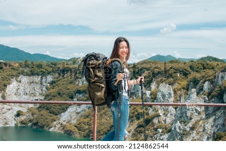 Asian beautiful woman wearing hat and casual clothes, smiling with happiness, adventure traveling alone and hiking on the top of mountains with backpack in summer vacation trip on weekend