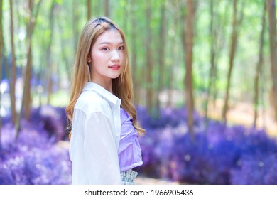 Asian beautiful woman wearing white long shirt smiles happily and stands in the purple flower garden as Background in natural theme. - Powered by Shutterstock