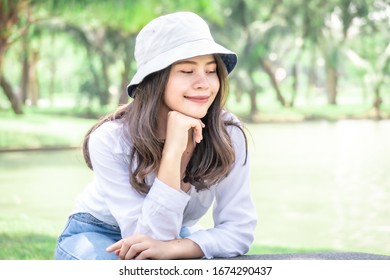 Asian beautiful woman with yellow skin, long black hair, wearing a white shirt, jeans, showing emotions in the morning nature park