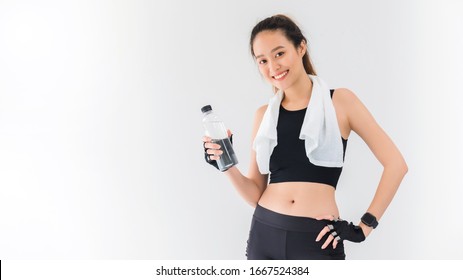 Asian beautiful women holding water bottle after play yoga and exercise on white wall background with copy space.Exercise for Lose weight, increase flexibility and tighten the shape.