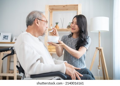 Asian beautiful young daughter support to elderly father on wheelchair. Attractive woman serving and feeding food to older patient grandfather in living room at home. Family Healthcare medical concept - Powered by Shutterstock