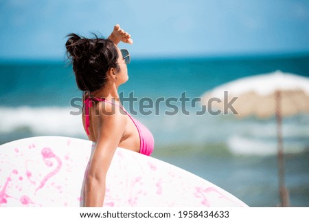 Asian beautiful young girl in bikini holding a surfboard at the beach.Summer Vacation. Water Sport.