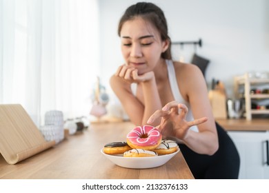 Asian beautiful young girl hungry and want to eat donut in kitchen. Attractive woman wear sport cloth feeling famished after exercies and pick up junk food unhealthy to eat, Food and health concept. - Shutterstock ID 2132376133
