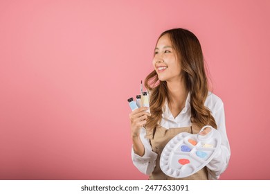 Asian beautiful young woman artist holding brush and paint palette, Happy female painting using paintbrush and palette with colors, studio shot isolated on pink background, Paintings and art equipment - Powered by Shutterstock