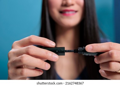 Asian Beauty Guru Showing Black Mascara At Camera Advertising Cosmetic Product Filming Video Tutorial For Vlogging Channel. Social Media Influencer Recording Make Up Review. Close Up