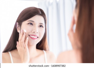 Asian  Beauty Woman Apply Lotion On Her Face In The Bathroom