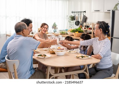 Asian big happy family have lunch on eating table together in house. Senior elder grandparent, young couple and little kid daughters feel happy, enjoying food in house. Activity relationship concept. - Powered by Shutterstock