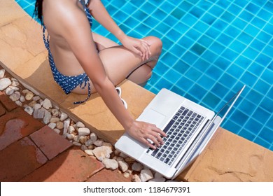 Asian Bikini Woman Sexy In Pool Using Laptop Computer Relaxing Young Asian Beautiful Female Resting In Vacation On Summer Season With Hat At Resort Swimming Pool Side.
