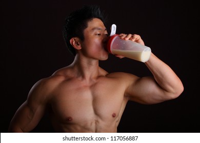 Asian Body Builder Drinking A Protein Shake On Black Background