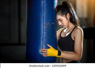 Asian boxing girls are standing hugging sandbags to meditate in the gym.