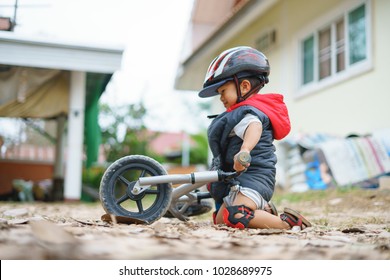 Asian Boy About 2 Years Is Riding Baby Balance Bike And Fall, Get Up On His Own, Playing And Learning Concept